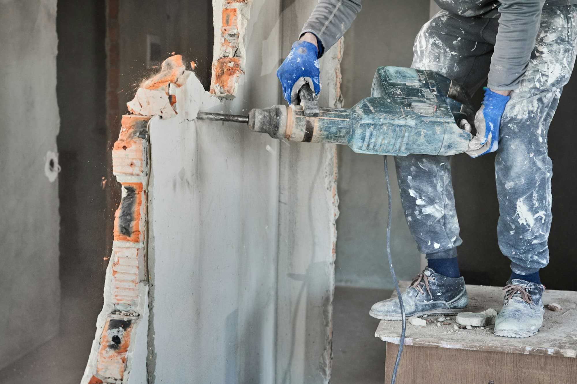 Cropped view workman with perforator during demolition wall.